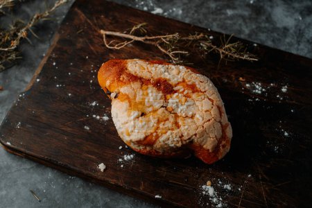 Photo for A colomba pasquale, a typical italian easter bread, on a wooden cutting board, placed on a dark rustic table - Royalty Free Image