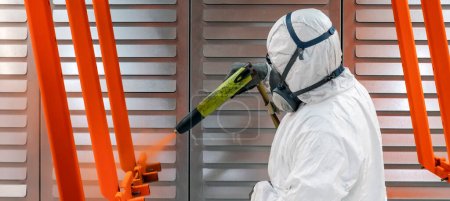 worker painting with a paint gun in a factory, France