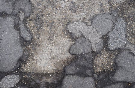 Téléchargez les photos : Dommages d'asphalte sur le plancher de chaussée abandonné montrant dalle de béton sous-jacente utile comme fond - en image libre de droit
