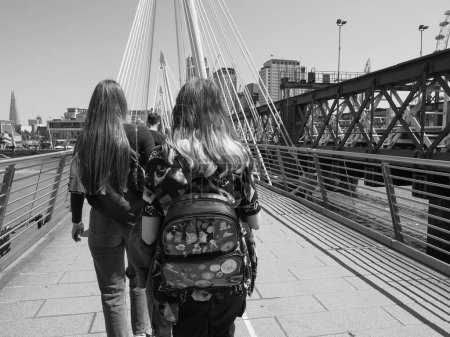 Photo for LONDON, UK - JUNE 08, 2023: People crossing Golden Jubilee Bridge over River Thames links Charing Cross to the South Bank and Waterloo in black and white - Royalty Free Image