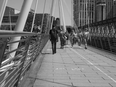 Photo for LONDON, UK - JUNE 08, 2023: People crossing Golden Jubilee Bridge over River Thames links Charing Cross to the South Bank and Waterloo in black and white - Royalty Free Image