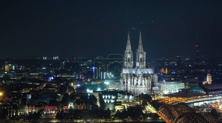 Nachtaufnahme des Kölner Doms Sankt Petrus, gotische Kirche und Hohenzollernbrücke über den Rhein in Köln