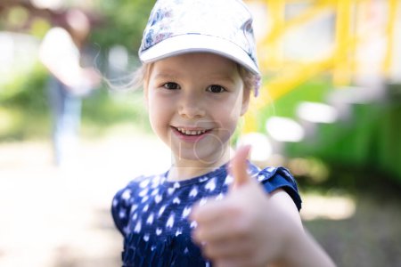 Photo for Happy young girl showing thumb up outdoors - Royalty Free Image