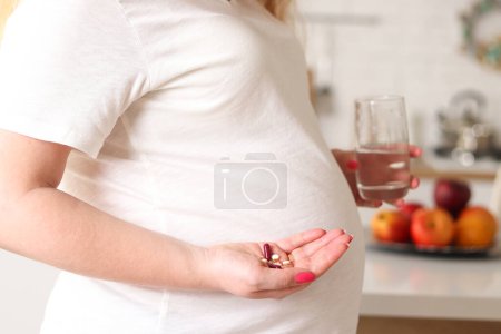 Photo for A pregnant woman takes vitamins and pills to maintain her pregnancy and improve her well-being. Selective focus. Concept of healthcare, medicine and pregnancy. - Royalty Free Image