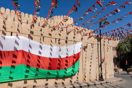Foto de Bandera nacional de Omán durante el Día de la Independencia. Arquitectura medieval tradicional en Nizwa, Omán. - Imagen libre de derechos
