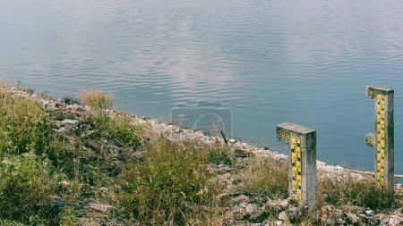 Téléchargez les photos : Un poteau en béton mesure la profondeur de l'eau dans le barrage. Paysage vue nature. - en image libre de droit