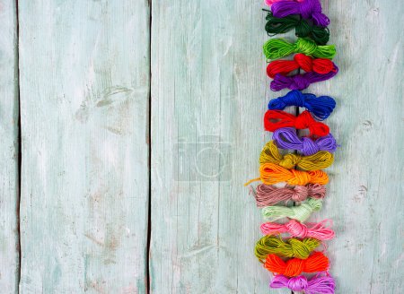 Foto de Conjunto de hilos multicolores para bordar en bacground de madera turquesa - Imagen libre de derechos