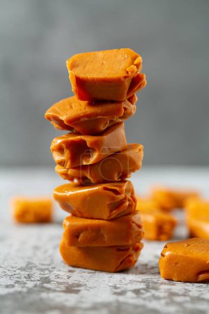 Photo for Soft caramel candies. Butterscotch toffee pieces on grey stone surface - Royalty Free Image