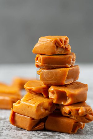 Photo for Soft caramel candies. Butterscotch toffee pieces on grey stone surface - Royalty Free Image