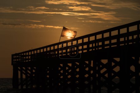 Sonnenuntergang ließ die amerikanische Flagge an einem Fischersteg in der Nähe der North Redington Shores, Tampa, Florida, glühen