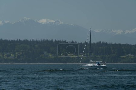Sail boat passing waters in Possession bay between Cama Beach and Whidbey Island, Camano State Park