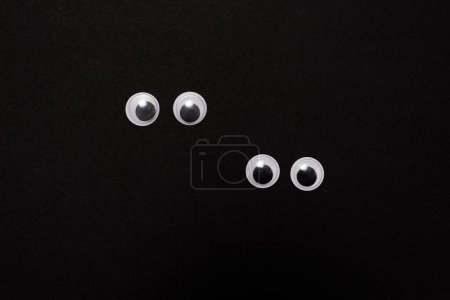 Photo for Pair of funny googly eyes on a black background with copy space - Royalty Free Image