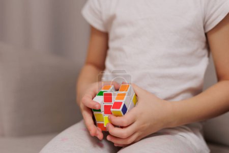 Photo for Close up of little girl playing with Rubik's cubeat home - Royalty Free Image