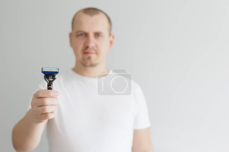 close up of man's hand showing a razor with copyspace