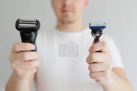 Man holding in hands and choosing between razor and electric razor