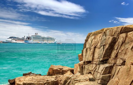 Téléchargez les photos : Vue du port depuis la côte rocheuse avec bateau de croisière au loin par une journée ensoleillée - en image libre de droit