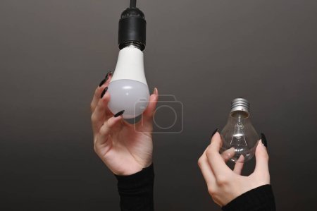 Téléchargez les photos : Le concept d'économie d'énergie. La nouvelle ampoule LED remplace l'ampoule à incandescence. Lampes dans les mains des femmes. - en image libre de droit