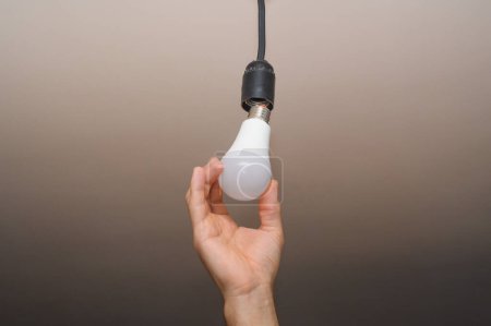 Téléchargez les photos : Replacement installation electric LED. in the man's hand is an electric bulb. - en image libre de droit