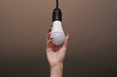 Téléchargez les photos : Installation of an LED lamp. Energy saving. in women's hands electric bulb - en image libre de droit