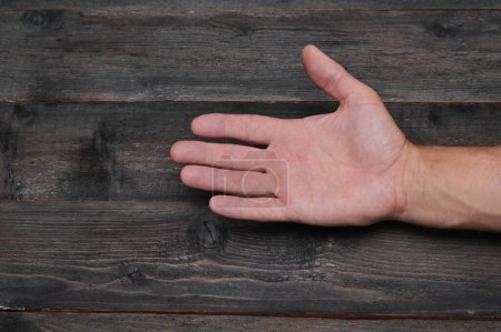 Foto de Primer plano de la palma. La mano de un hombre sobre un fondo de tablas de madera. - Imagen libre de derechos
