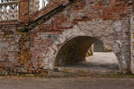 an arch under the crumbling stairs of an old building