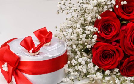 a bouquet of red roses and a gift in a box