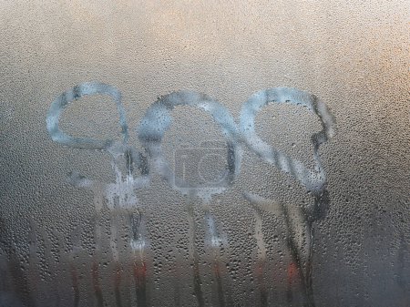 The word sos is written on the wet glass of the window.