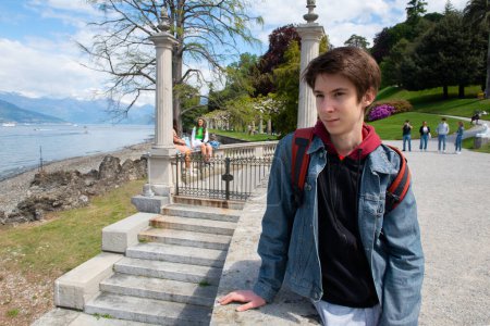 Foto de Guapo adolescente caminando en el parque con gran paisajismo y hermosas plantas, primavera en el lago Como, belleza en la naturaleza, Italia, Lombardía - Imagen libre de derechos