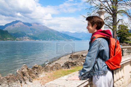 Foto de Guapo adolescente caminando en el parque con una gran vista al paisaje con el lago Como y las montañas de los Alpes, belleza en la naturaleza en primavera, Italia, Lombardía - Imagen libre de derechos