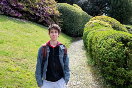 Photo for Handsome teen boy walking at park of villa Melzi with great landscaping and beautiful plants in spring, beauty in nature at springtime, Italy, Lombardy - Royalty Free Image