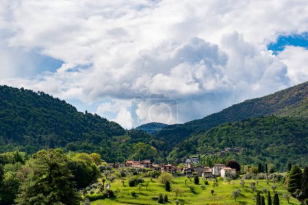 Photo for Village among green hills on the slopes of the Italian Alps not far from Lake Como, photo taken in spring. Picturesque landscape - Royalty Free Image