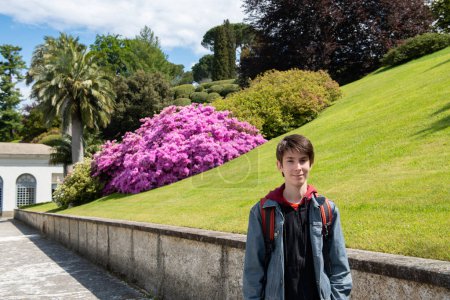 Téléchargez les photos : Beau garçon adolescent marchant au parc de la villa Melzi avec un grand aménagement paysager et de belles plantes au printemps, beauté dans la nature au printemps, Italie, Lombardie - en image libre de droit
