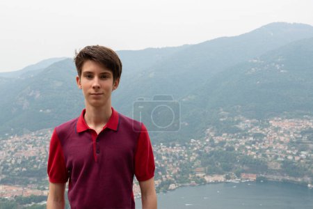 Foto de Guapo adolescente posando sobre una gran vista con el paisaje del lago de Como y las montañas de los Alpes, belleza en natur, Lombardía, Italia, Europa - Imagen libre de derechos