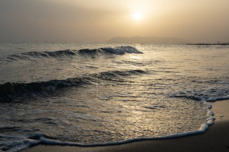 Foto de Mar. Hermosa puesta de sol dorada en la costa mediterránea con una iluminación inusual a través de la neblina del aire - Imagen libre de derechos