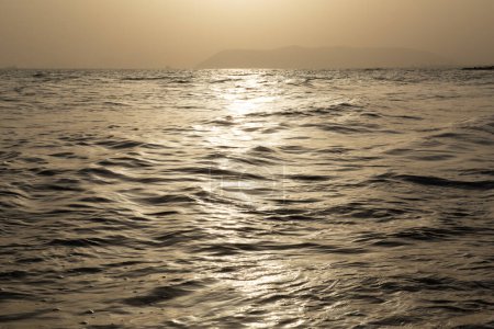 Téléchargez les photos : Vue sur mer. Beau coucher de soleil doré sur la côte méditerranéenne avec éclairage insolite à travers la brume aérienne - en image libre de droit