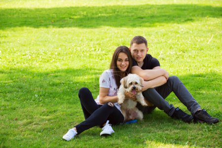 Photo for Young couple with puppy. Portrait of attractive happy smiling young woman and man holding cute little dog, summer park outdoor. - Royalty Free Image