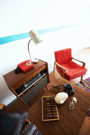 Photo for Cosy vintage room with retro radio turntable, telephone, standart lamp, armchair as well and abacus, camera, glasses. Interior of 20th century, nostalgia - Royalty Free Image