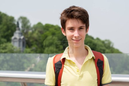 Photo for Young handsome teen boy wearing yellow t-shirt stands on glass bridge in Kyiv, Ukraine, summer outdoor - Royalty Free Image