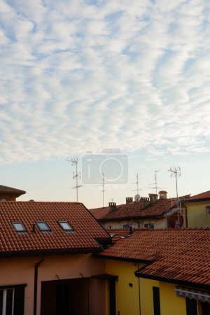 Téléchargez les photos : Toits carrelés de maisons avec antennes dans une petite ville d'Italie sur fond de ciel nocturne - en image libre de droit