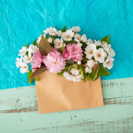 Téléchargez les photos : Sakura en fleurs et cerisier blanc. Enveloppe avec des fleurs printanières sur fond de papier décoratif froissé bleu. Concept de design printanier - en image libre de droit