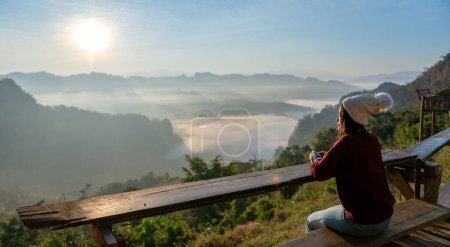 Turista asiática está sentada y disfrutando de la salida del sol de la mañana y la niebla en la montaña. viajar en Mae Hong Son, Tailandia