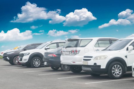 Photo for Cars parking in a row in stock background. Vehicle transportation trip inventory merchandise. Car parked in large asphalt parking lot with white cloud and blue sky background. Outdoor parking lot - Royalty Free Image
