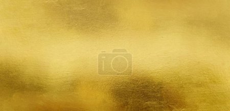 Gold Wand Textur Hintergrund. Gelb glänzende Goldfolienfarbe auf Wandoberfläche mit Lichtreflexion, lebendige goldene Luxus-Tapete, horizontal