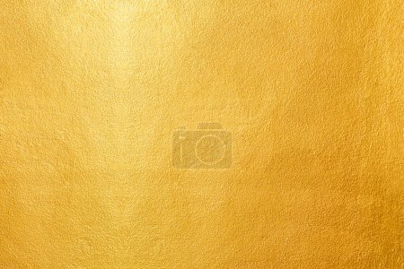 Gold wall texture background. Yellow shiny gold paint on wall surface with light reflection, vibrant golden luxury wallpaper shee