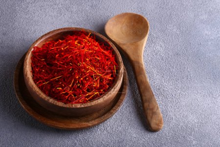 Photo for Saffron in a wooden bowl on the table, healthy food - Royalty Free Image