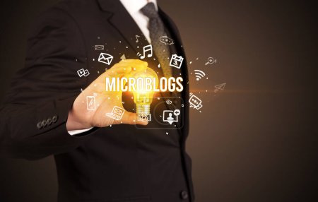 Foto de Empresario sosteniendo bombilla con inscripción MICROBLOGS, concepto de redes sociales - Imagen libre de derechos