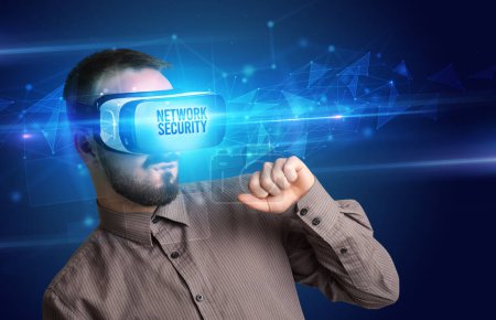 Téléchargez les photos : Homme d'affaires regardant à travers des lunettes de réalité virtuelle avec inscription NETWORK SECURITY, concept de cybersécurité - en image libre de droit