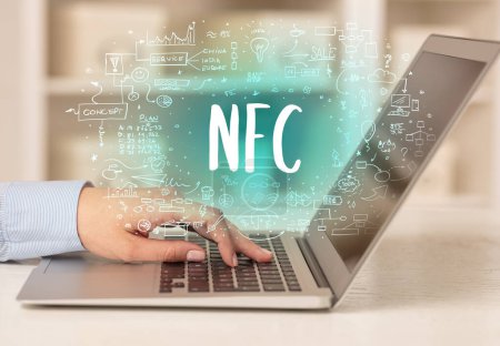 Téléchargez les photos : Main de travail sur un nouvel ordinateur moderne avec abréviation NFC, concept de technologie moderne - en image libre de droit