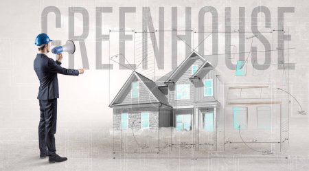 Photo for Young engineer holding blueprint with GREENHOUSE inscription, house planning concept - Royalty Free Image