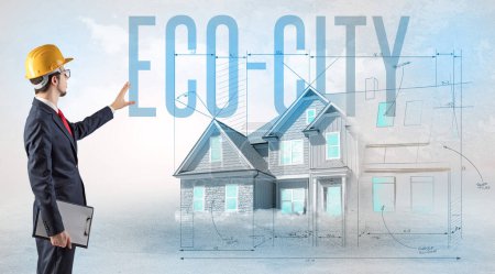 Photo for Young engineer holding blueprint with ECO-CITY inscription, house planning concept - Royalty Free Image